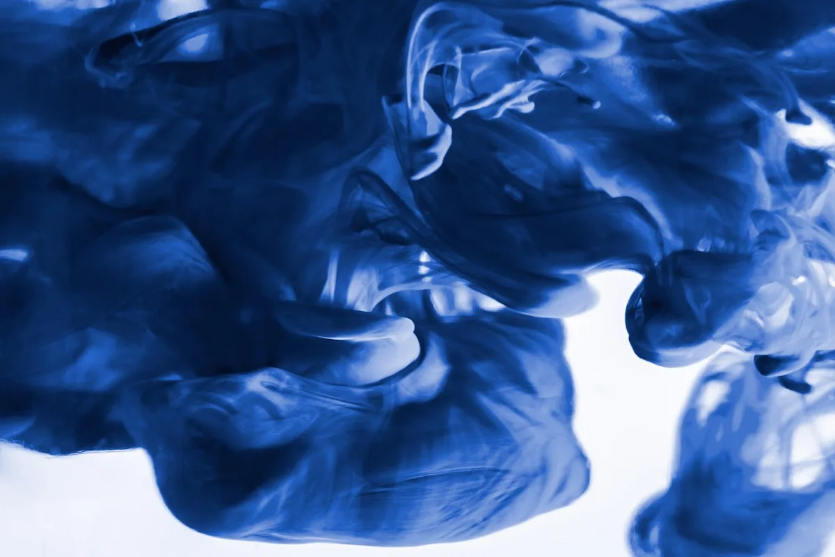 Deep blue liquid dispersing through clear water